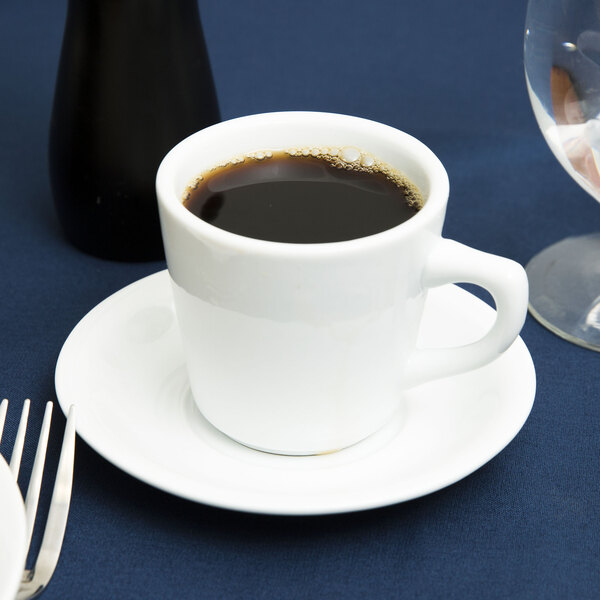 A white saucer with a cup of coffee on it.