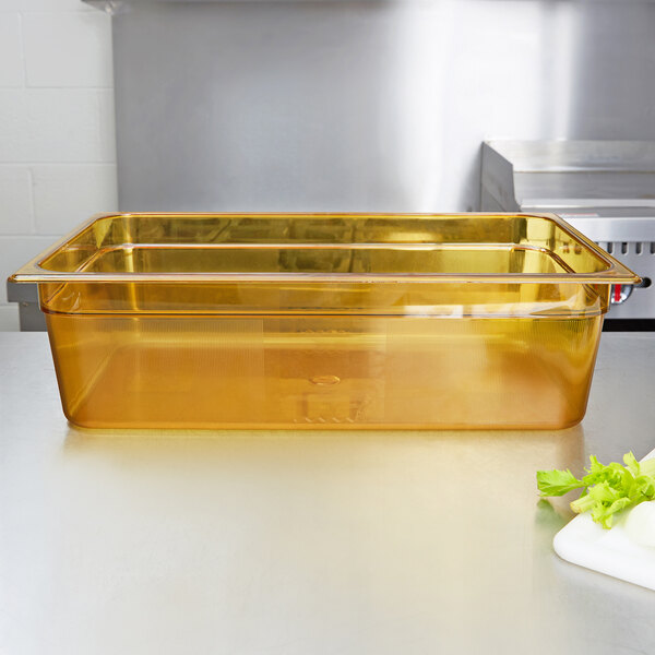 A yellow Rubbermaid plastic food pan on a counter filled with lettuce and other vegetables.