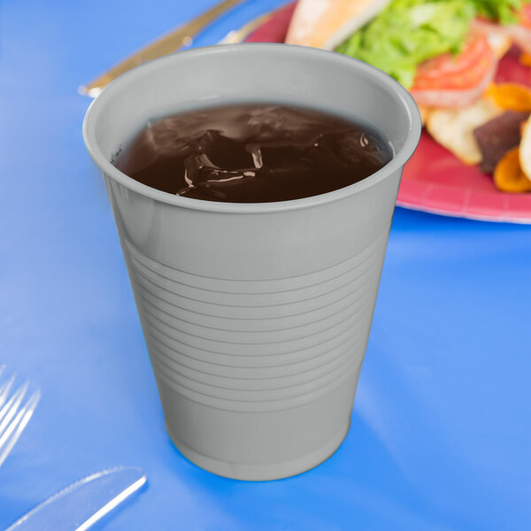 A shimmering silver plastic cup filled with liquid on a blue table.