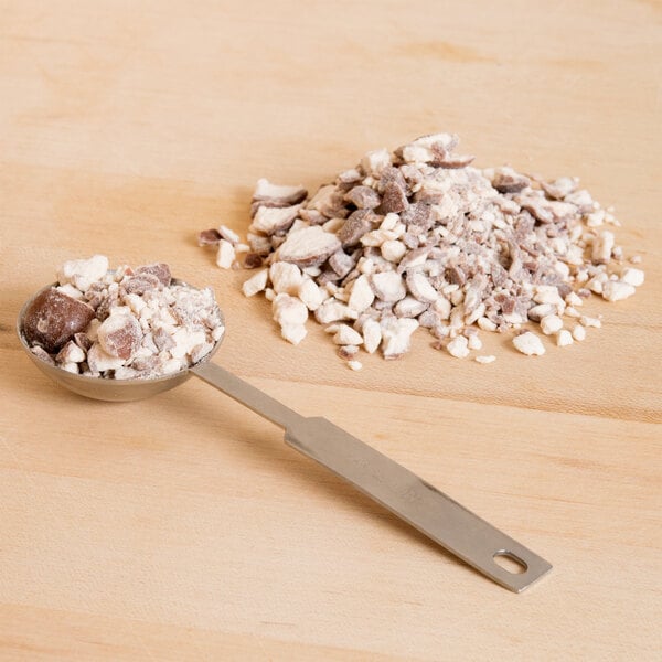 A bowl of chocolate ice cream with a spoon and Whoppers malt balls on top.
