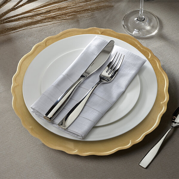 A white charger plate with a scalloped gold rim.