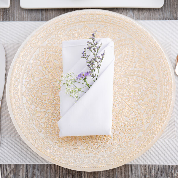A Charge It by Jay gold glass charger plate with a napkin and flowers on it.