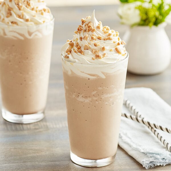 Two glasses of Big Train Toffee Mocha blended ice coffee topped with whipped cream and nuts.