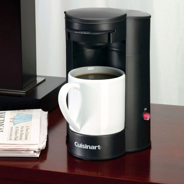 A Conair Cuisinart coffee maker on a table next to a white mug.