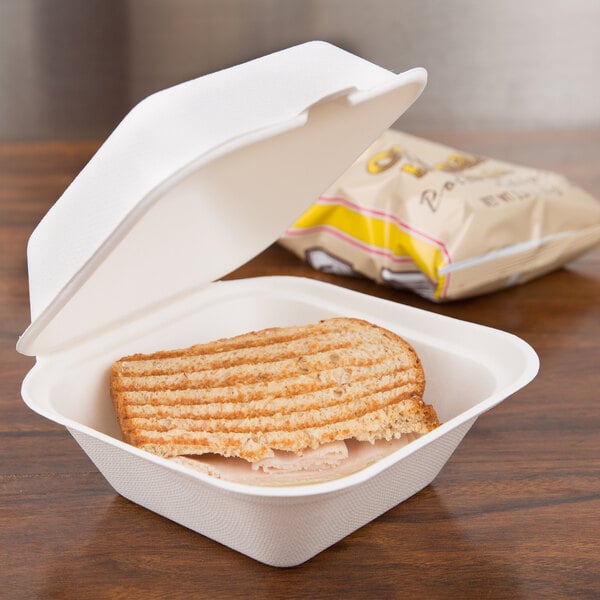 A sandwich in a Bare by Solo sugarcane take-out container on a table.