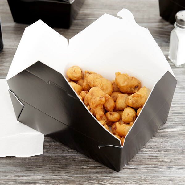 A black Fold-Pak Bio-Pak take-out box filled with fried food.