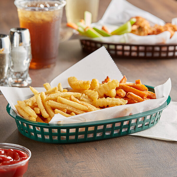 A forest green Tablecraft platter basket filled with french fries and ketchup on a table.