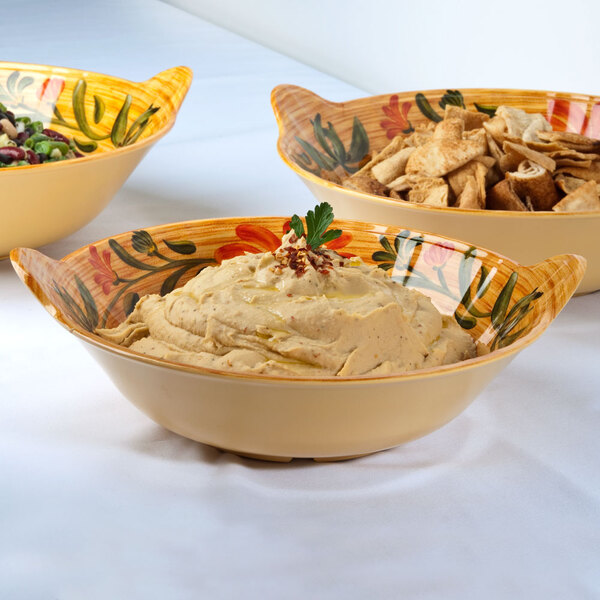 A bowl of hummus in a GET Venetian bowl on a table with other bowls of food.