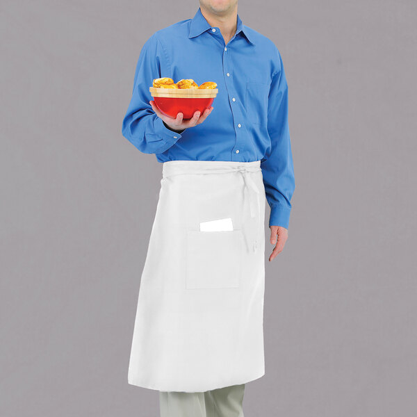 A man in a blue shirt and white Chef Revival bistro apron holding a bowl of food.