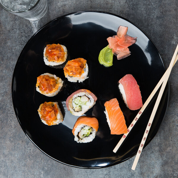 A plate of sushi with chopsticks on a black Elite Global Solutions round organic edge plate.