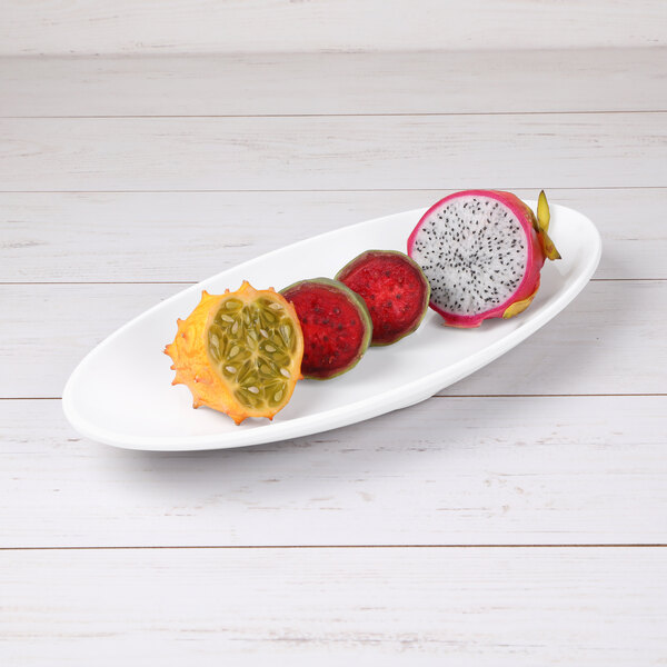 A white Elite Global Solutions oblong plate with dragon fruit, cut in half, on a table with other fruit.