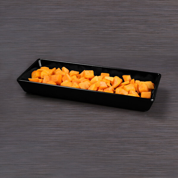 A black rectangular melamine bowl with diced orange fruit in it.