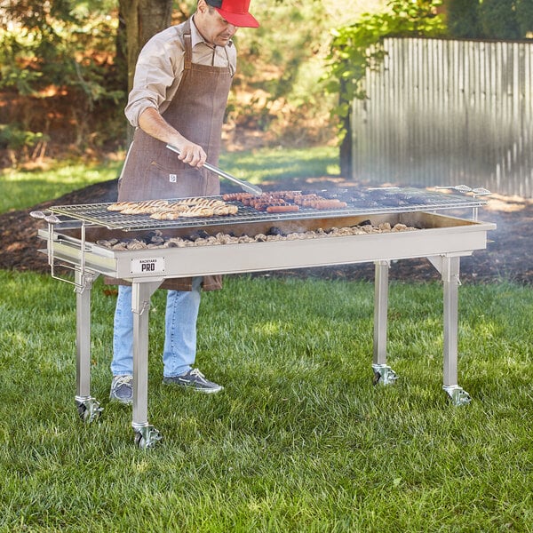 A man cooking meat on a Backyard Pro stainless steel charcoal grill with adjustable grates.
