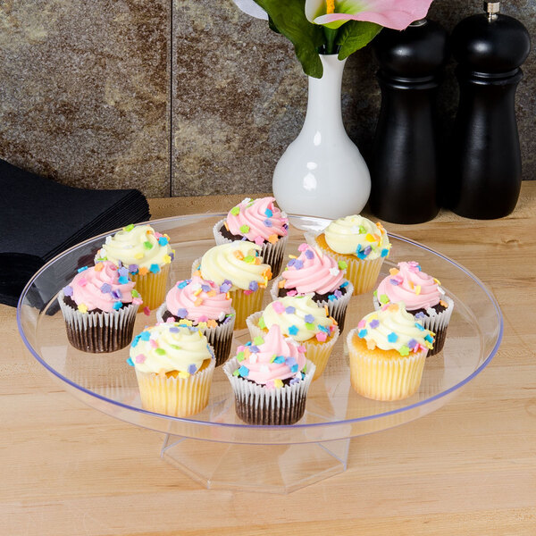 A Fineline clear plastic cake stand with cupcakes on it.