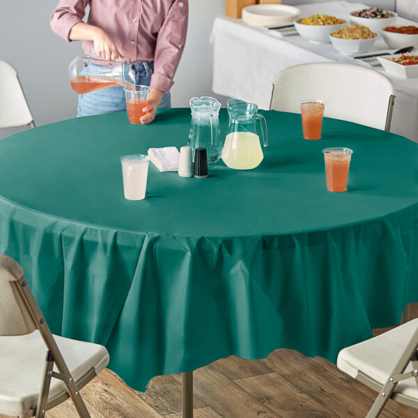 A woman sitting at an outdoor table with a Creative Converting Hunter Green table cover.