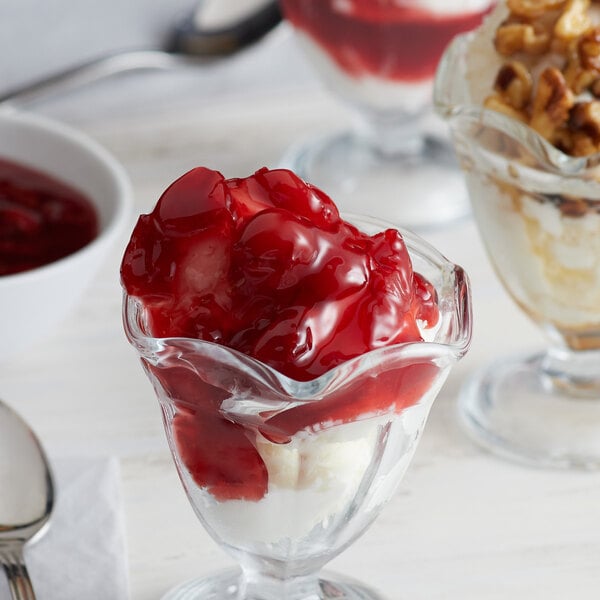 A glass cup of I. Rice cherry dessert topping on a dessert with ice cream and cherries.