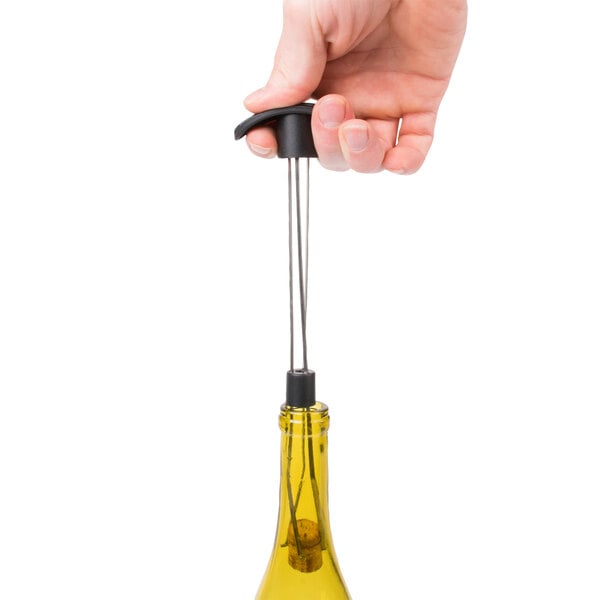 A hand using a Franmara cork retriever to remove a cork from a wine bottle.