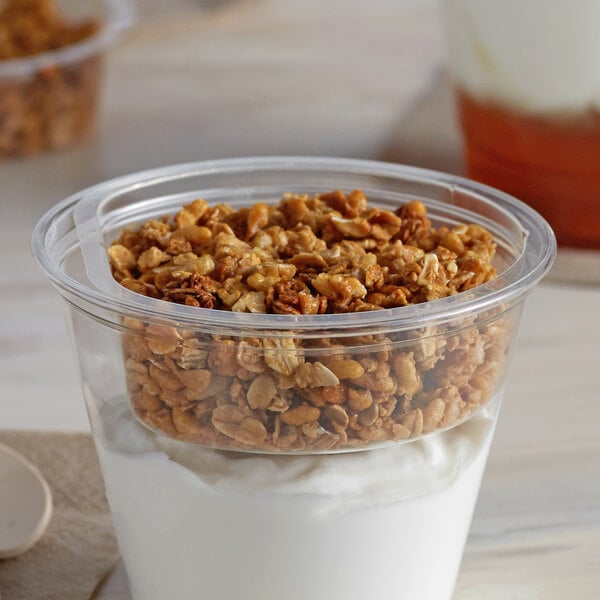 A clear plastic Fabri-Kal parfait insert filled with yogurt and granola on a white plate.