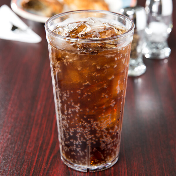 A close up of a GET clear plastic tumbler filled with brown soda and ice.