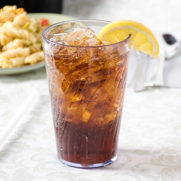 A clear plastic tumbler of ice tea with a lemon wedge on the side.