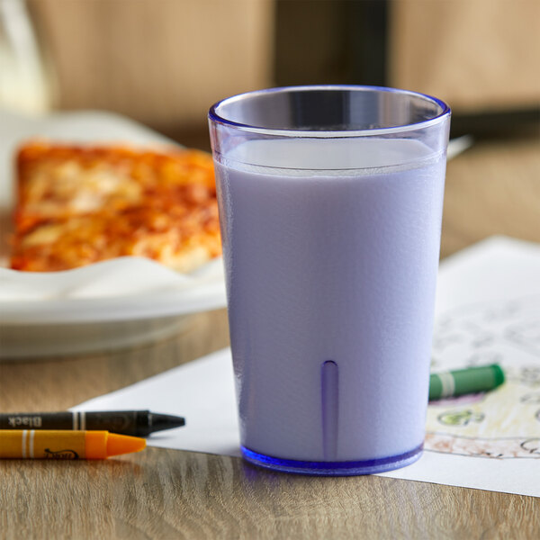 A close-up of a blue GET SAN plastic tumbler filled with milk on a table.