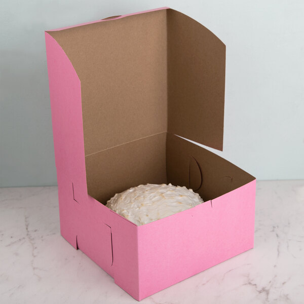 A pink cake box with a white cake inside.