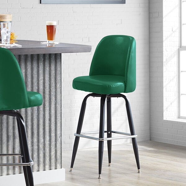 A Lancaster Table & Seating Pine Green Vinyl Bar Stool with black legs.