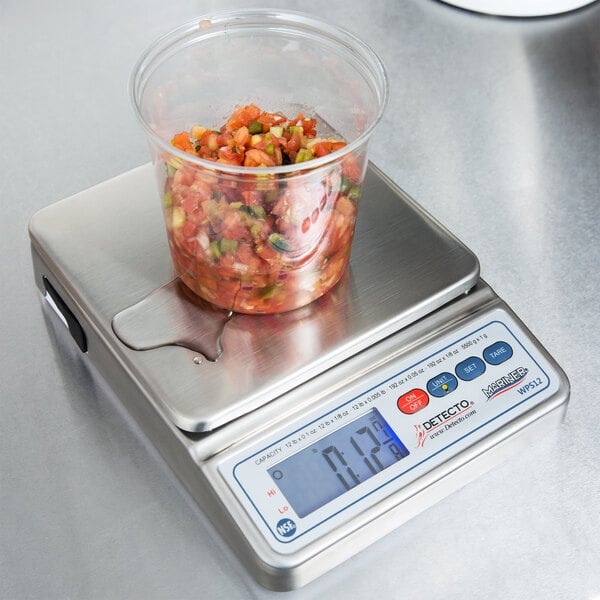 A Cardinal Detecto digital portion scale with a container of chopped tomatoes on it.