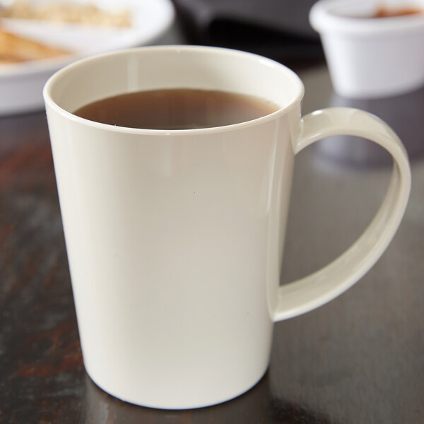 A white Carlisle Tritan mug filled with brown liquid on a table.
