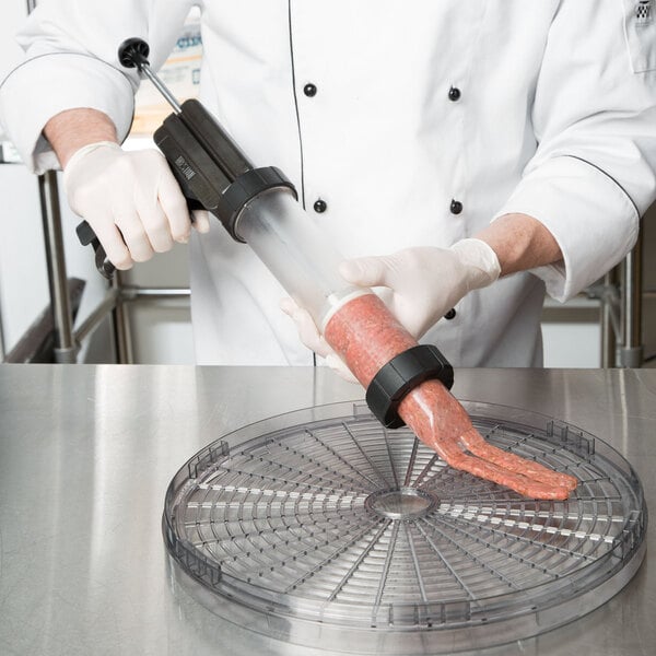 A chef holding a Weston Jerky Gun Jr. tube filled with meat.