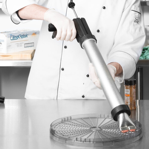 A person in a white coat using a Weston Jerky Shooter to put food into a container with a plastic lid with holes.