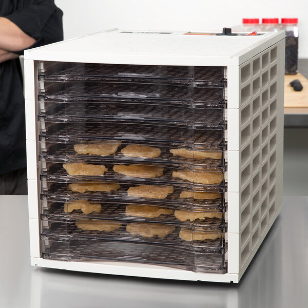 A white rectangular plastic tray with brown food inside on a Weston food dehydrator tray.