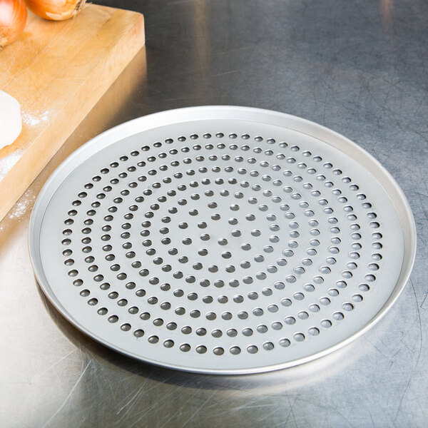 A metal pizza pan with holes in it sitting on top of a metal pizza pan.