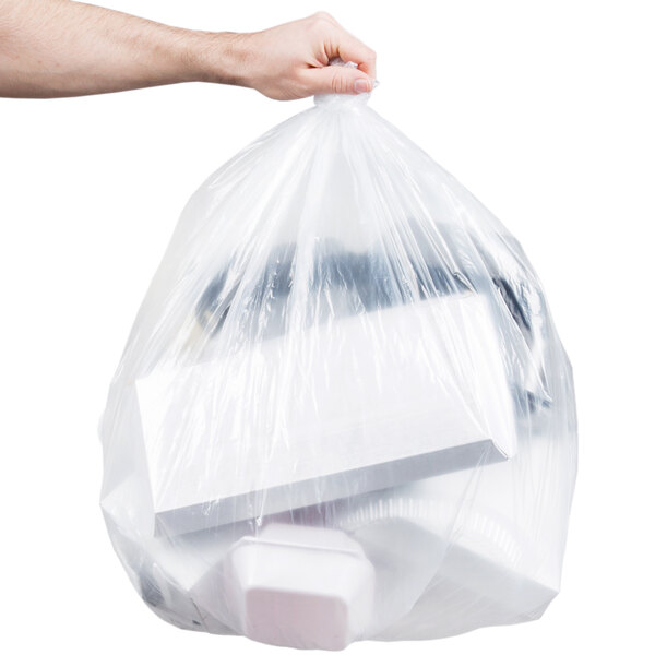 A hand holding a full Berry low density clear plastic bag of white objects.