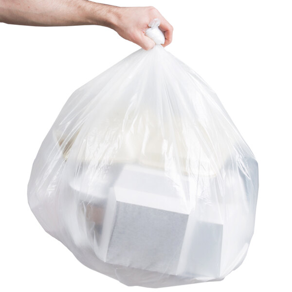A person's arm holding a Berry low density clear trash bag full of garbage.
