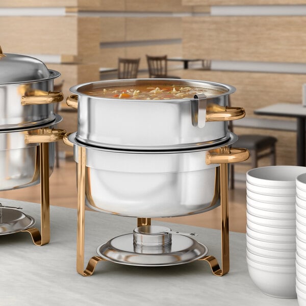 A Choice Deluxe round gold accent soup chafer on a table in a hotel buffet.