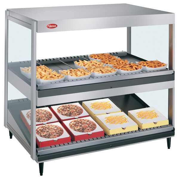 A Hatco countertop food warmer with trays of french fries and pizza on a counter.