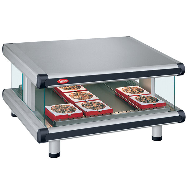 A Hatco slanted glass display case with pizza on a shelf.