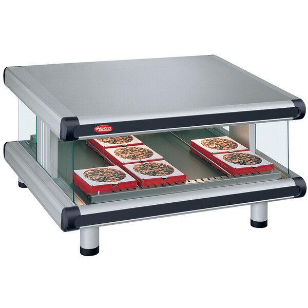 A Hatco countertop food warmer with a slanted shelf holding trays of pizza.