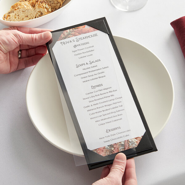A person holding a menu in a clear vinyl sheet protector on a plate.