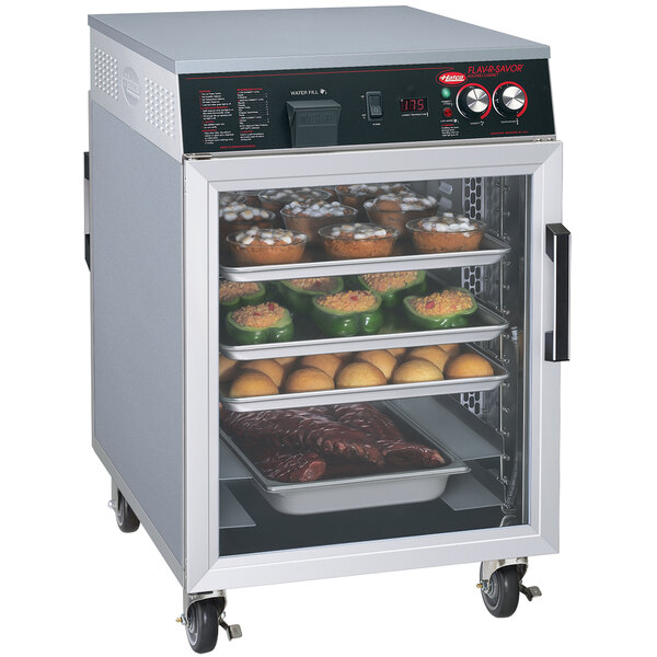 A Hatco Flav-R-Savor holding cabinet with trays of food in a outdoor catering setup.