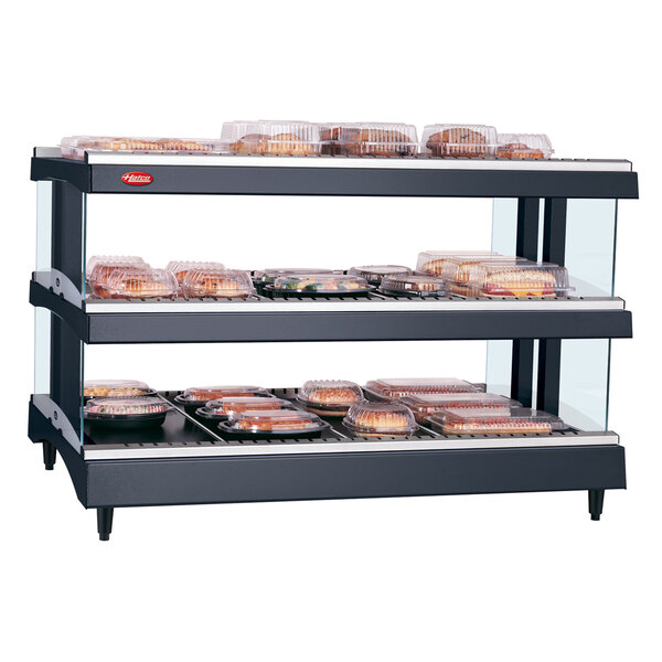 A Hatco countertop heated glass merchandising warmer with shelves of food inside.
