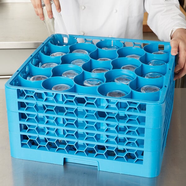 A person holding a Carlisle blue plastic glass rack with clear glasses inside.