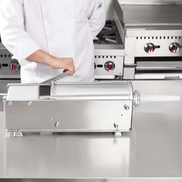 A chef using a Tre Spade horizontal sausage stuffer with stainless steel sides.