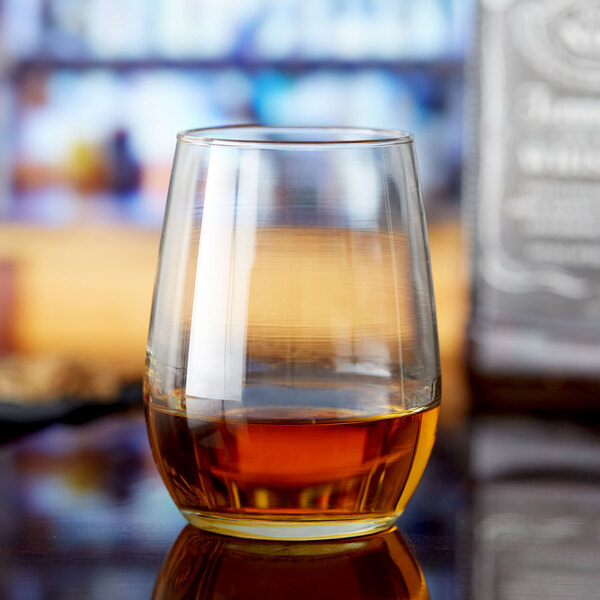 A Libbey stemless taster glass filled with brown liquid on a table.