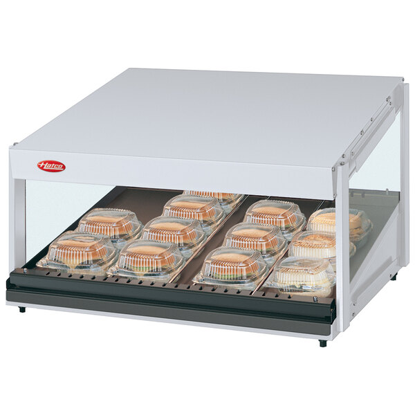 A Hatco countertop food warmer with sandwiches on a slanted shelf.