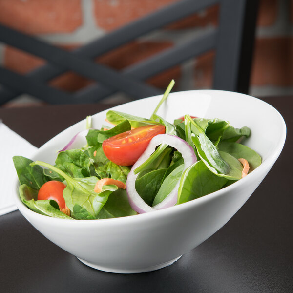 A Tuxton TuxTrendz Linx white china bowl filled with salad with tomatoes, onions, and spinach.