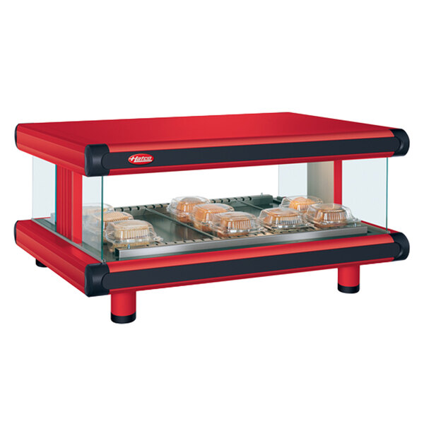 A red and black Hatco countertop food warmer with a single shelf on a bakery display counter.