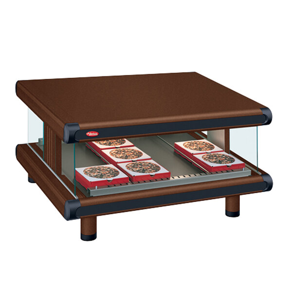 A brown rectangular Hatco countertop food warmer with a glass top on a table with trays of food.