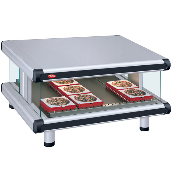 A Hatco countertop food warmer with pizzas on a slanted shelf.